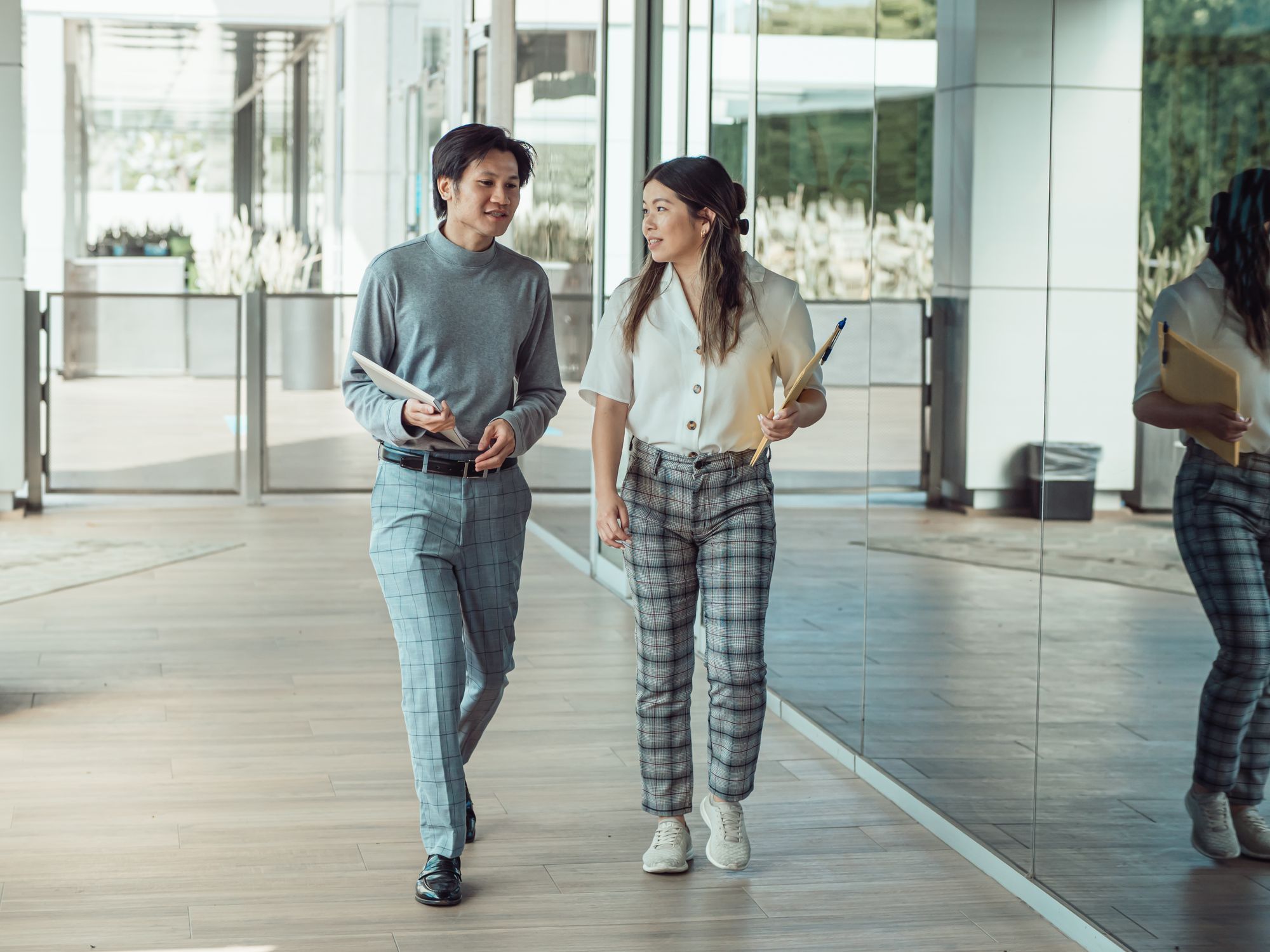 Two colleagues walking and talking through a modern office lobby